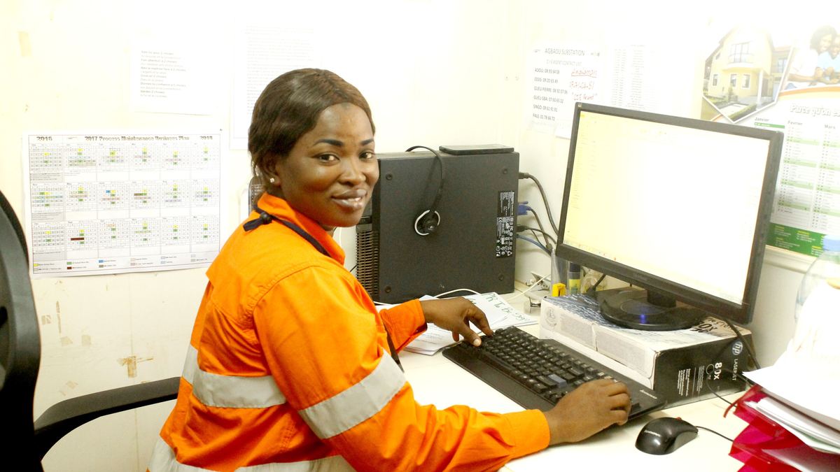 Collaboratrice en tenue de chantier saisissant ses données sur un poste de travail